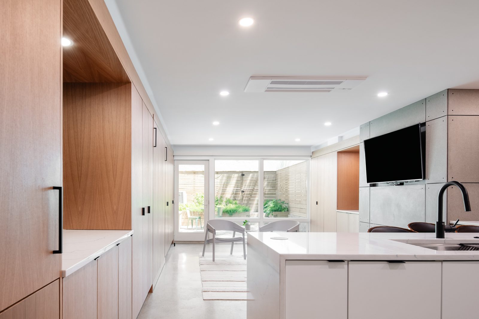 The same space now a continuous run of cabinetry, with glass doors open to the garden