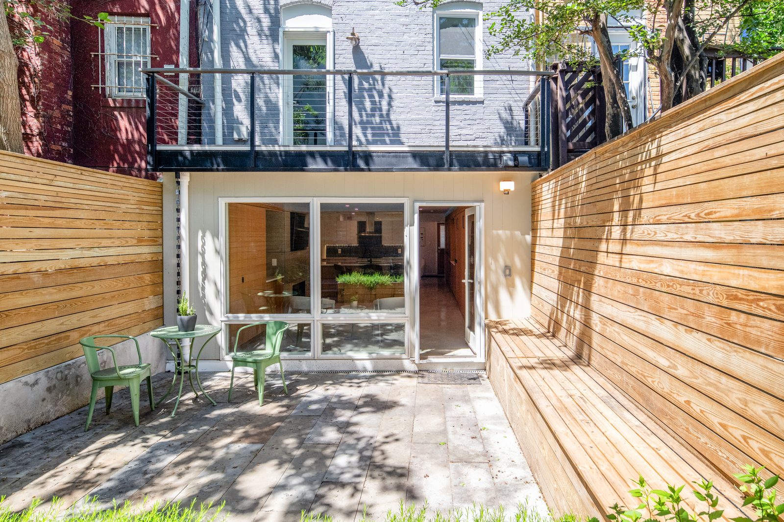 The same yard now a stone patio with seating, framed by cedar fencing