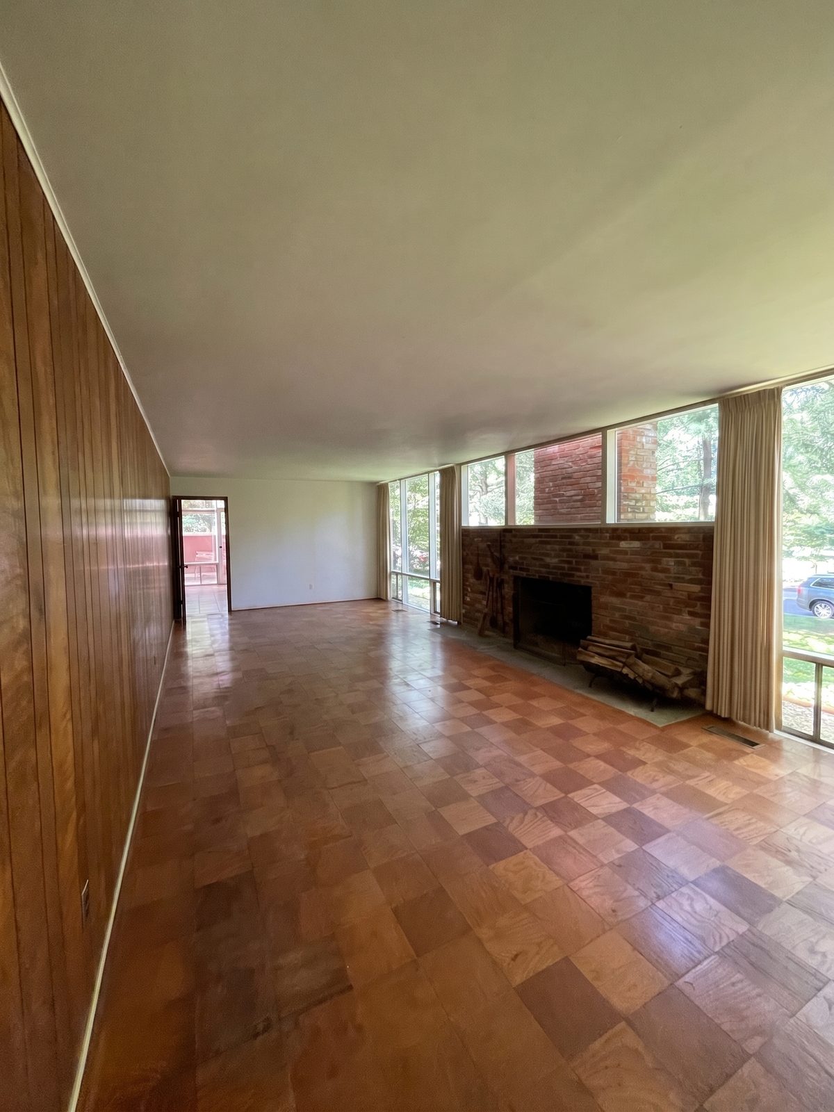 The living room before, wood panelling and a red brick fireplace
