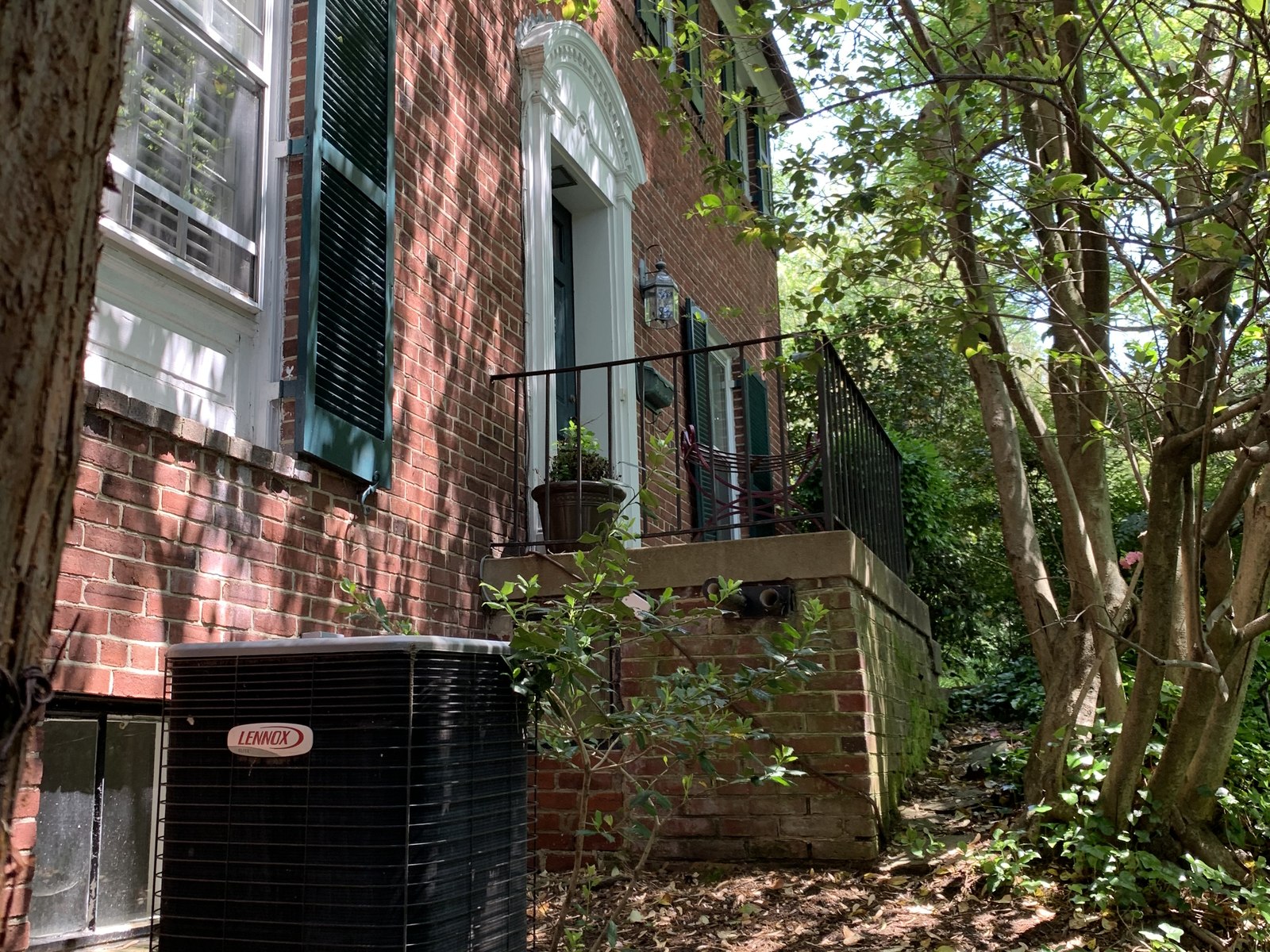The existing house on its sloped side lot, foundation exposed at grade