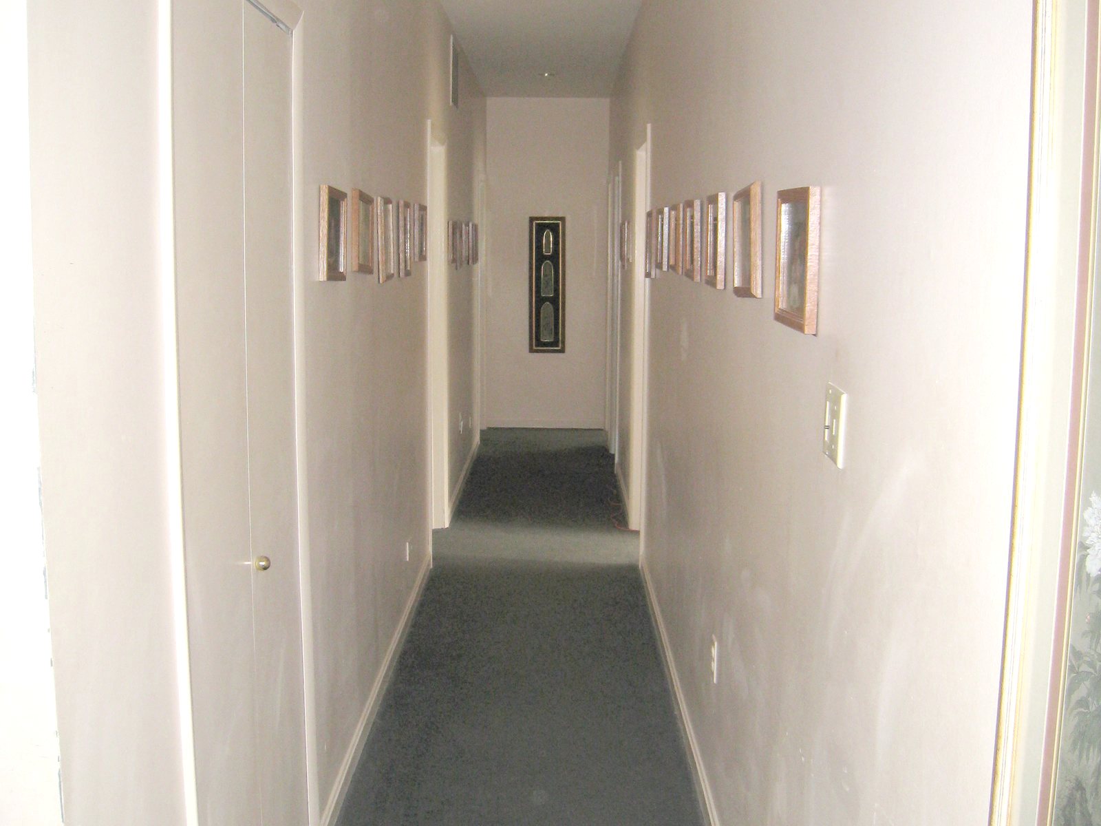A narrow carpeted corridor lined with framed pictures