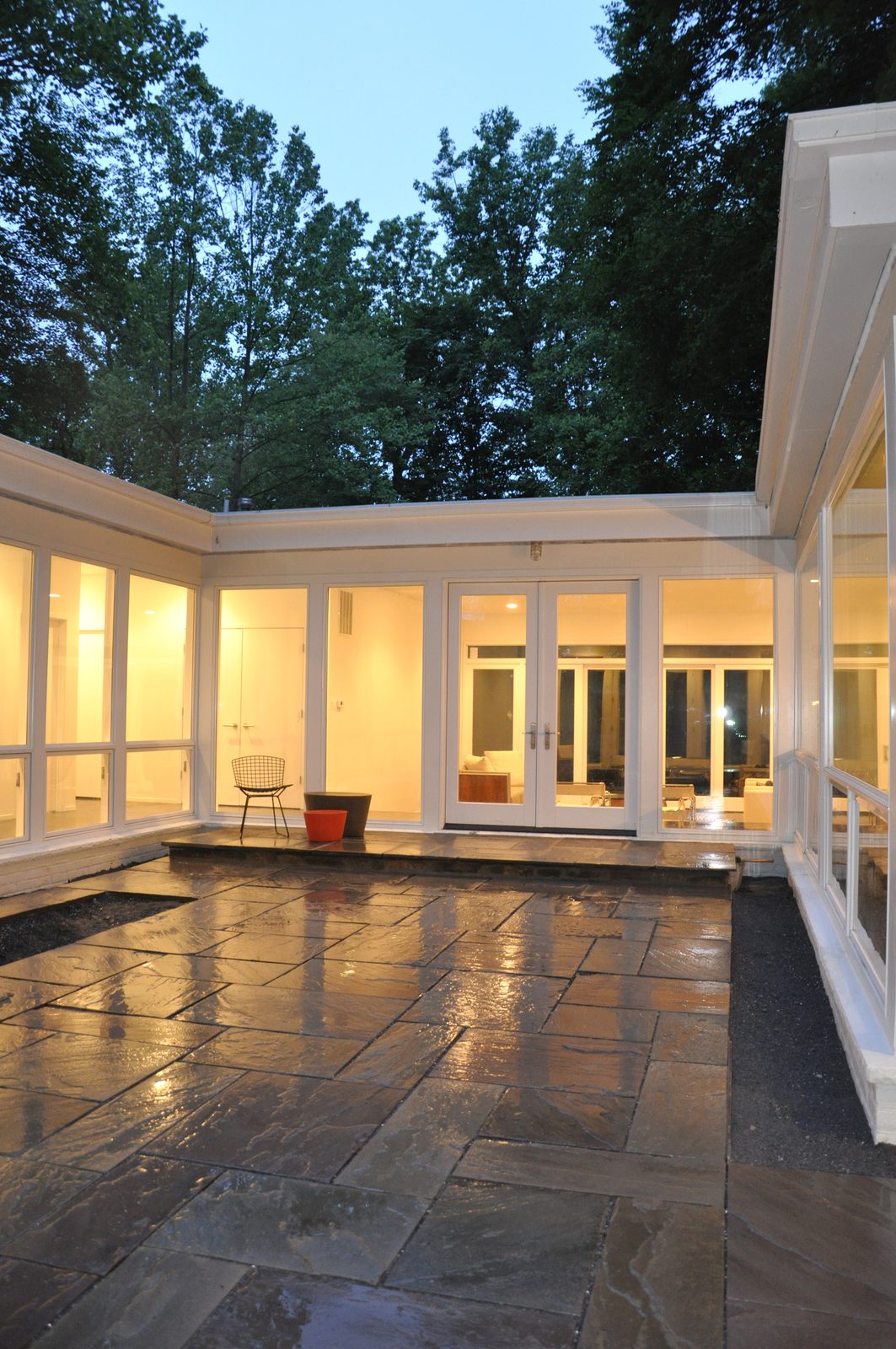 The finished courtyard at dusk, stone paving and lit glass on three sides