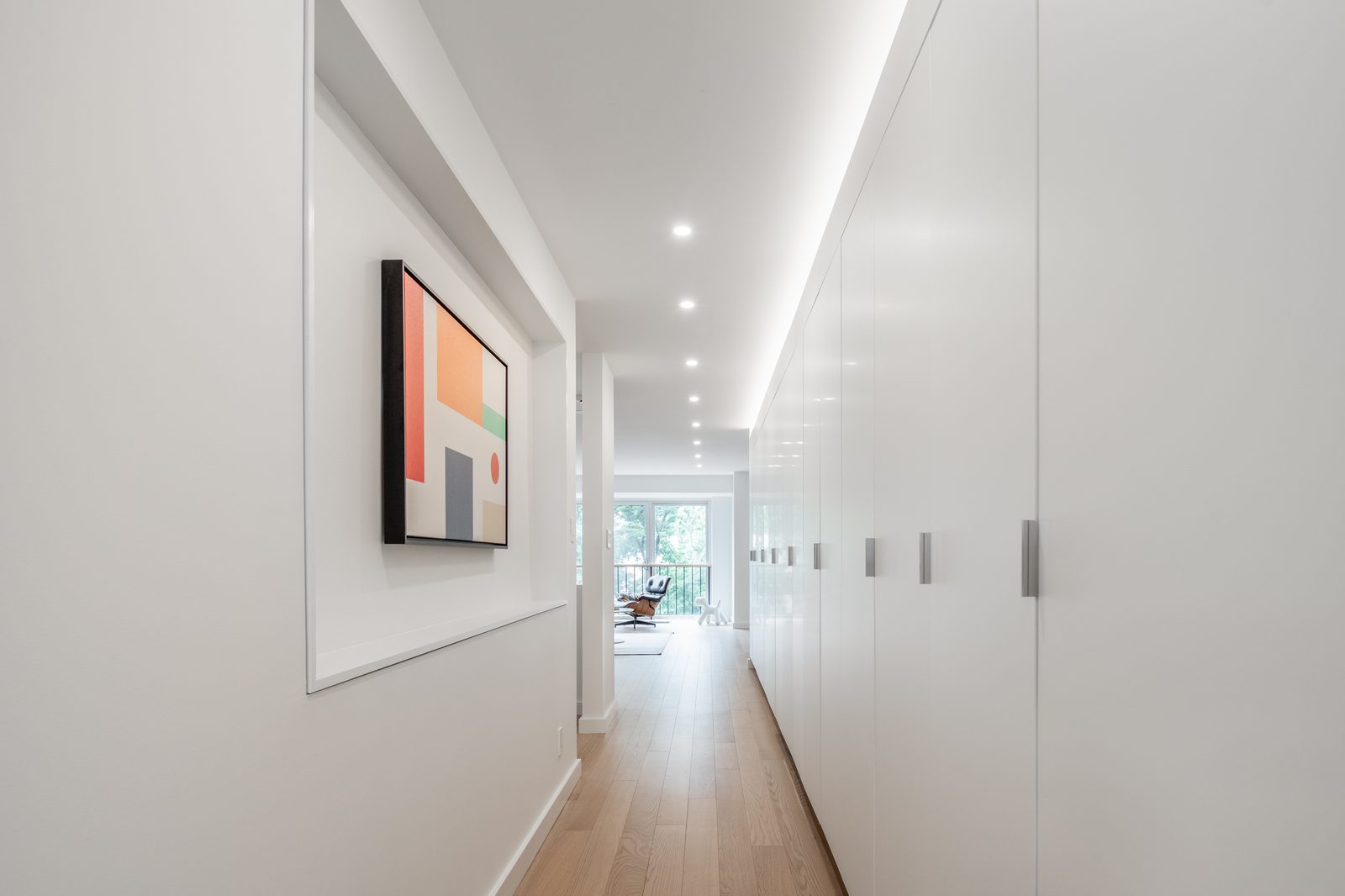 The same hallway now full-height storage on one side, and a single piece of art