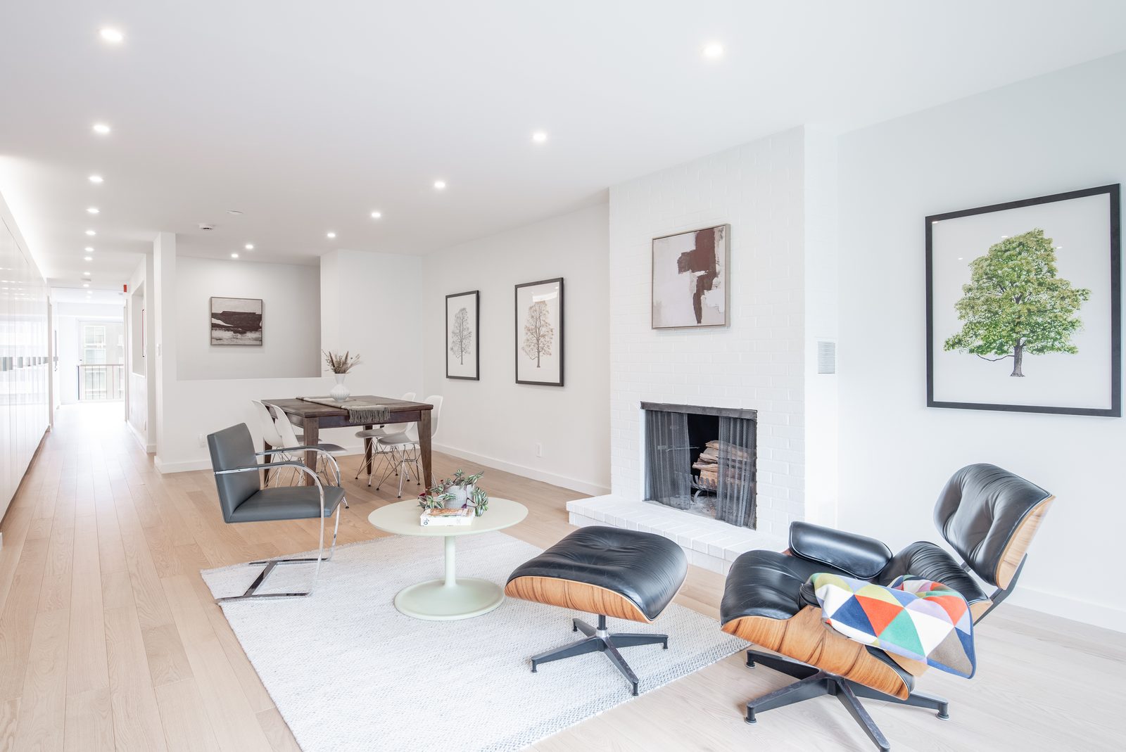 The same room now open and bright, table to fireplace to lounge chair